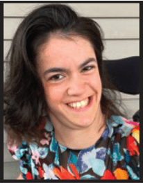 Sara Young, Portrait. A white woman with dark brown hair who is a wheelchair user wearing a colorful shirt, smiling.